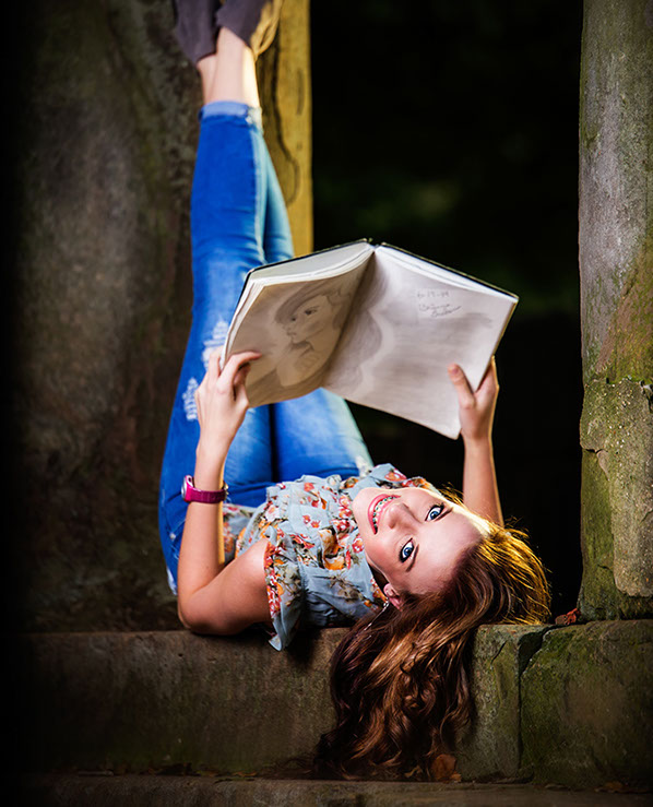 Sipsey Valley High School senior picture by a Tuscaloosa photographer high school senior girl lying upside down looking at an art book