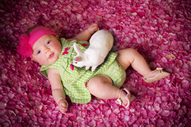 Adorable baby girl on a bed of flowers with a live bunny. Taken by a Tuscaloosa, Alabama baby photographer.